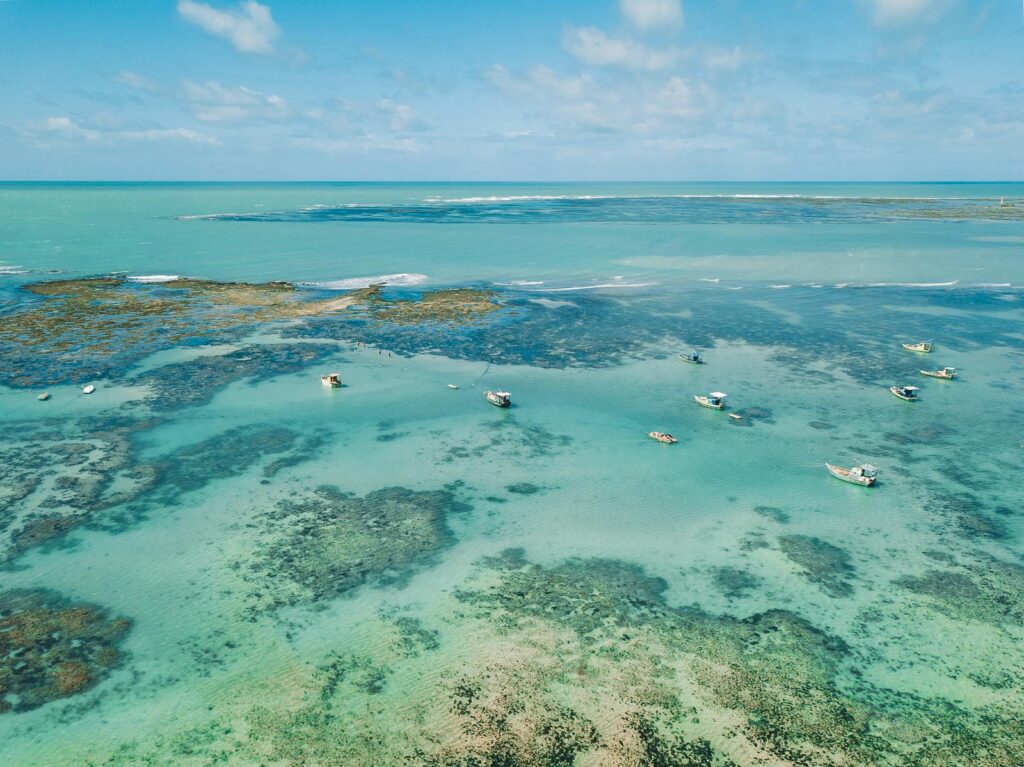 Vista aérea do mar azul em Maceió, uma das praias mais bonitas do Nordeste para sua próxima viagem